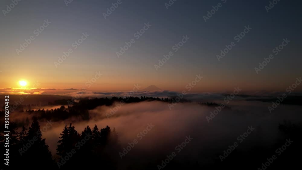 Aerial: foggy fire sky sunrise over Mount Rainier, also known as Tahoma, with clouds and skyscape in Cascade Range, Mount Rainier National Park, west-central Washington state, USA, pan drone shot Aerial: foggy fire sky sunrise over Mount Rainier, also known as Tahoma, with clouds and skyscape in Cascade Range, Mount Rainier National Park, west-central Washington state, USA, pan drone shot