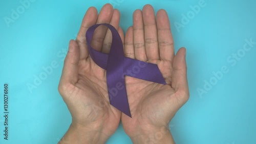 Footage video 4k. Hands holding purple or violet ribbon on blue. Pancreatic Cancer ,Testicular Cancer Awareness, Cancer Survivor, Leiomyosarcoma, World Cancer Day. Healthcare, insurance concept.