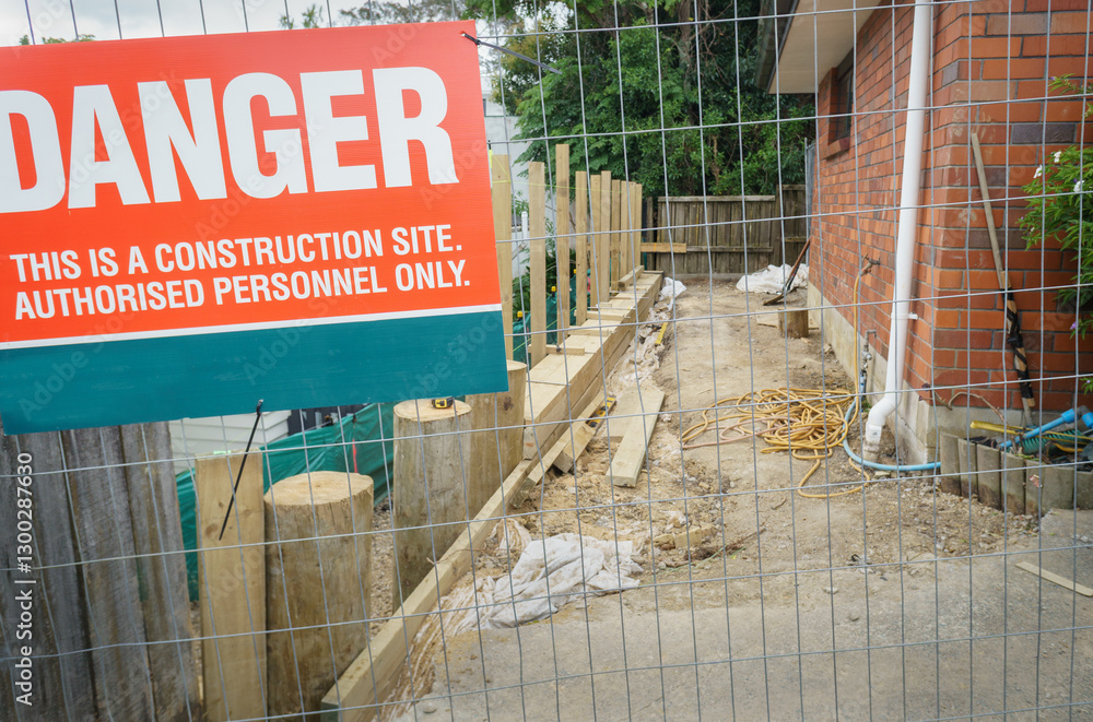 Danger sign on metal protection fence. Construction site for residential retaining wall rebuild. Auckland.