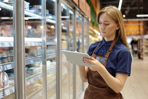 Waist up portrait of young woman working in supermarket and using tablet for stock managements, copy space