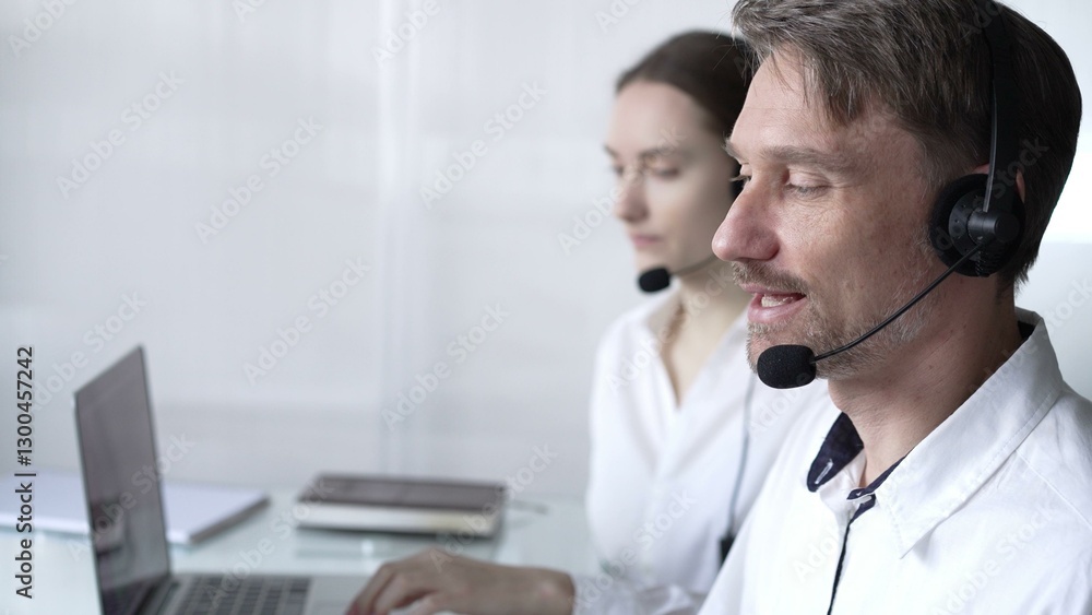 Happy smiling male call center operator in white casual shirt is assisting clients online, providing customer support and answering inquiries. Business call center operators Happy smiling male call center operator in white casual shirt is assisting clients online, providing customer support and answering inquiries. Business call center operators