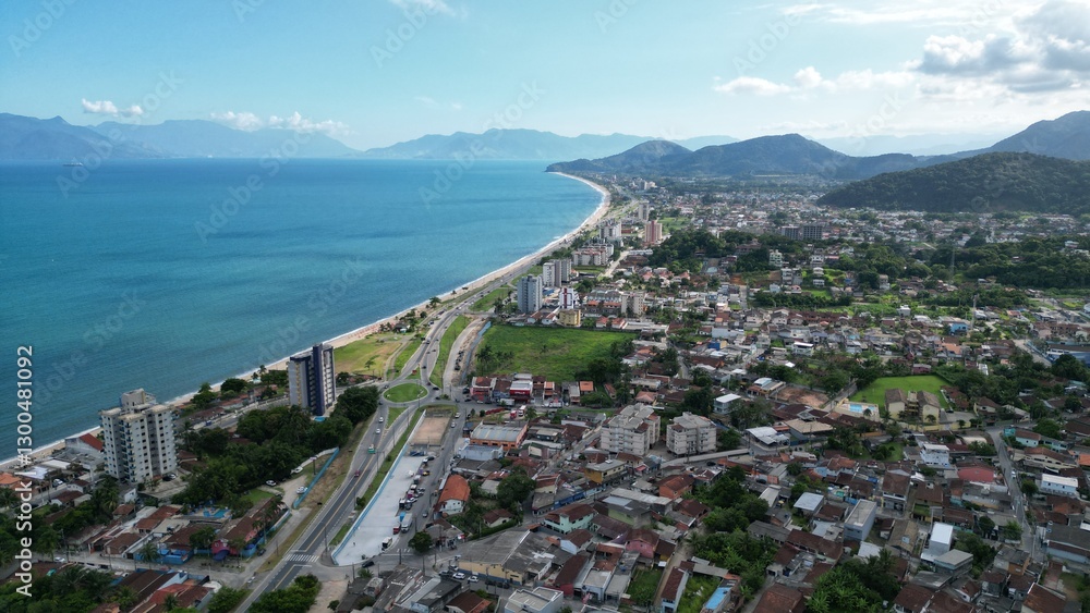 Fototapeta premium Linda vista aerea com drone sobre o mar com montanhas e cidade ao fundo com cores vibrantes.