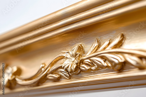 Close-up of an ornate, gilded picture frame with floral and leaf details, showcasing craftsmanship and elegant design against a clean, bright backdrop.