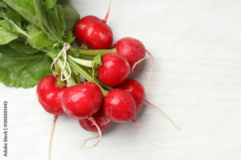 Fototapeta premium Bunch of fresh radishes on white wooden table, top view. Space for text