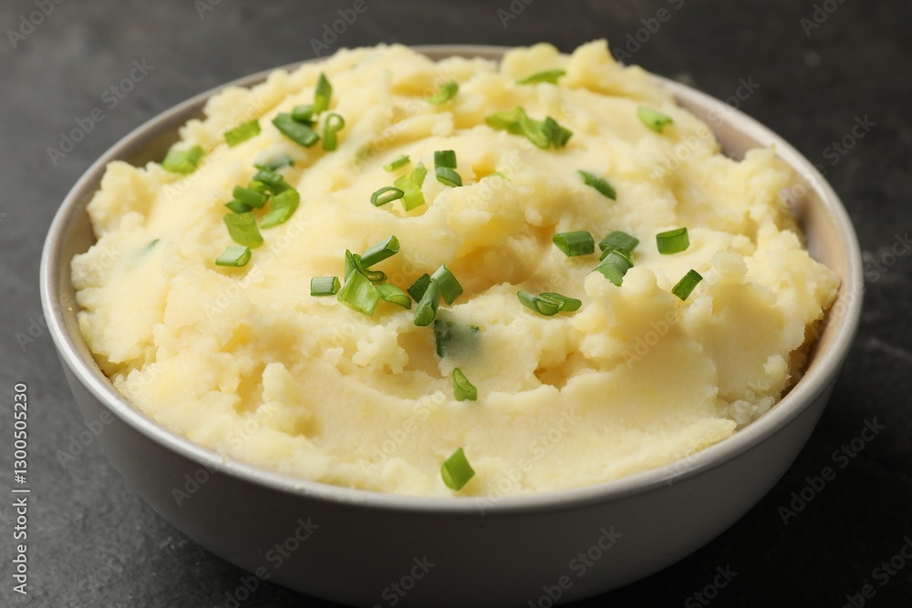 Delicious mashed potato with green onions in bowl on black table, closeup Delicious mashed potato with green onions in bowl on black table, closeup