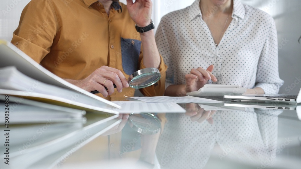 Two accountants conducting a financial audit in their office, closely examining documents with a magnifying glass and calculator. Taxes, audit in business
