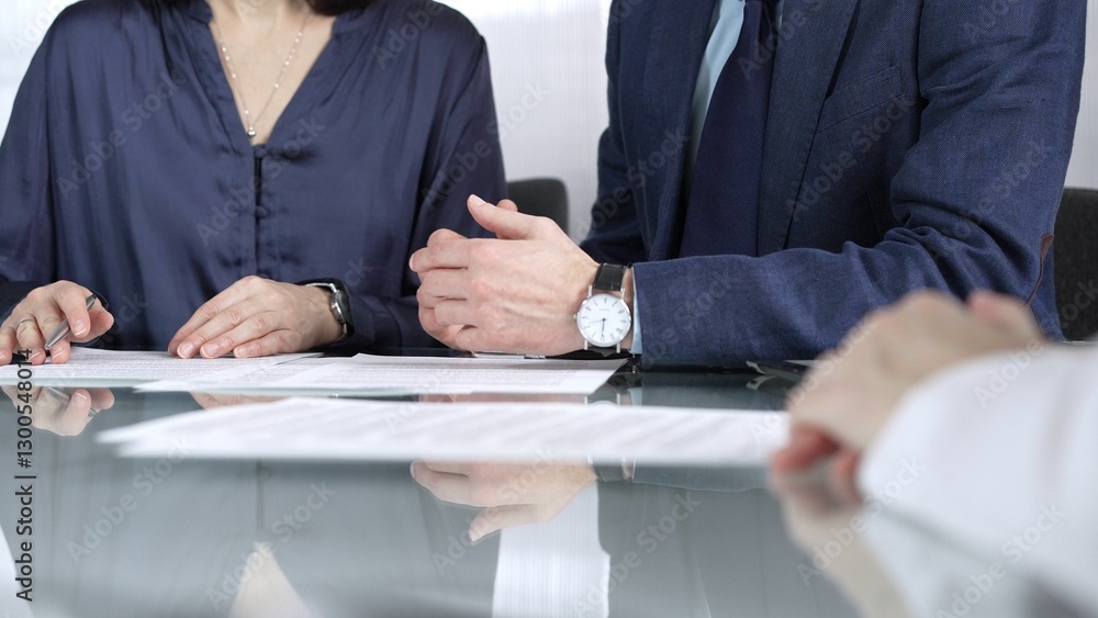 Business people reviewing contract terms during a meeting, negotiating and making decisions together. Business people concept, close up Business people reviewing contract terms during a meeting, negotiating and making decisions together. Business people concept, close up