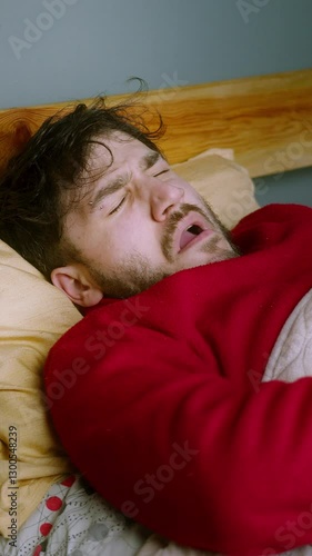 Sleepy Man Waking Up and Yawning in Bed with Alarm Clock Ringing ,vertical video