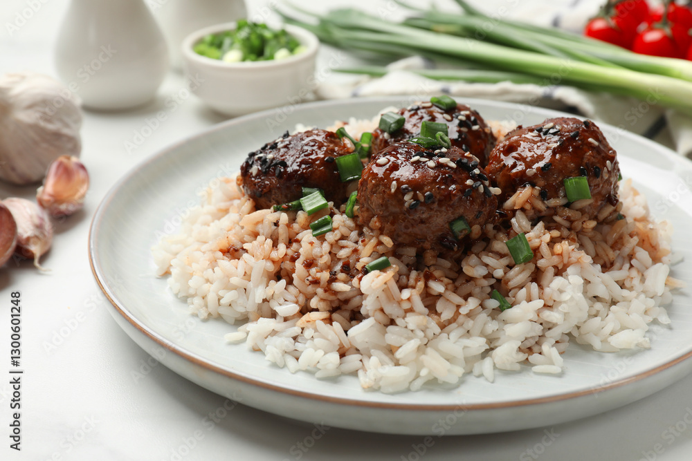 Delicious rice with meatballs, sauce and green onions on white table, closeup Delicious rice with meatballs, sauce and green onions on white table, closeup