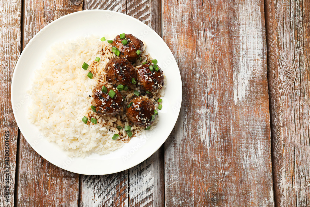 Delicious rice with meatballs, sauce and green onions on wooden table, top view. Space for text Delicious rice with meatballs, sauce and green onions on wooden table, top view. Space for text