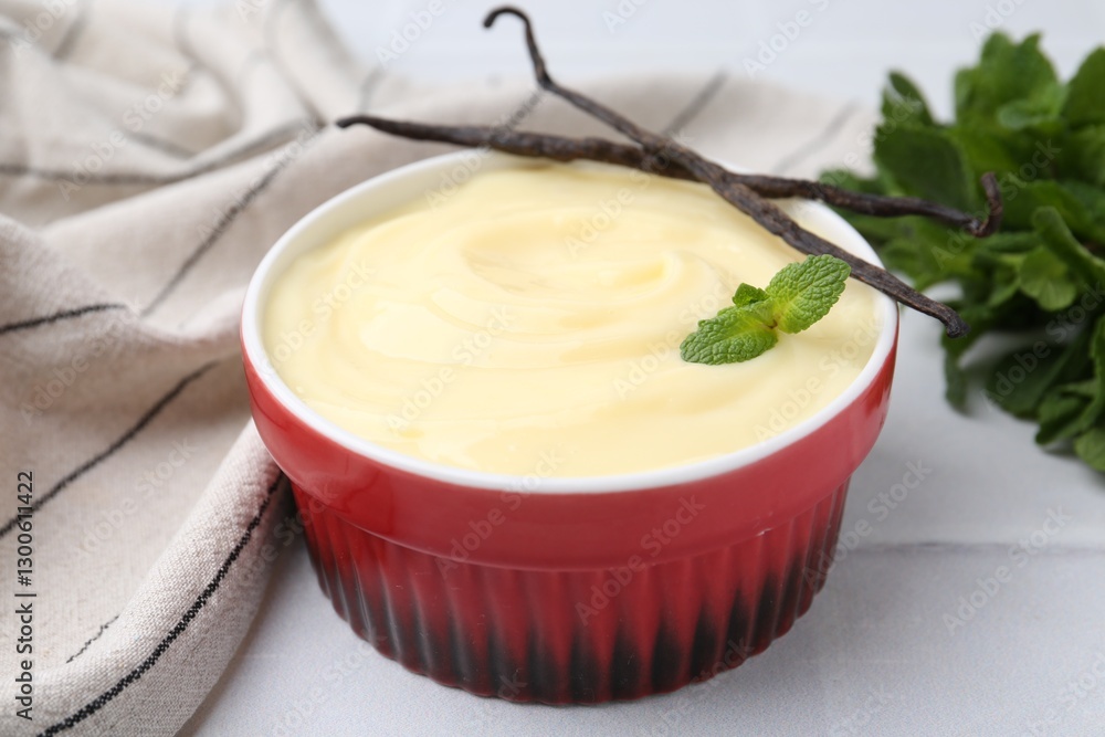 Tasty vanilla pudding, mint and pods on white tiled table, closeup Tasty vanilla pudding, mint and pods on white tiled table, closeup