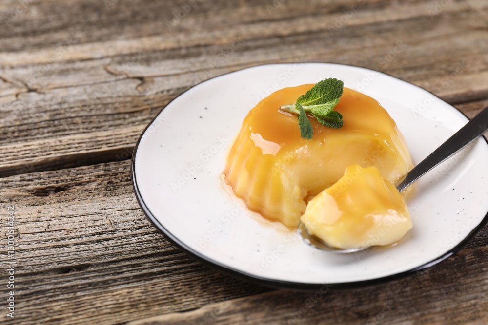 Delicious pudding with caramel sauce and mint served on wooden table, closeup. Space for text Delicious pudding with caramel sauce and mint served on wooden table, closeup. Space for text