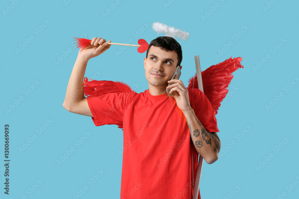 Young man dressed as Cupid with arrow talking by mobile phone on blue background. Valentine's Day celebration Young man dressed as Cupid with arrow talking by mobile phone on blue background. Valentine's Day celebration