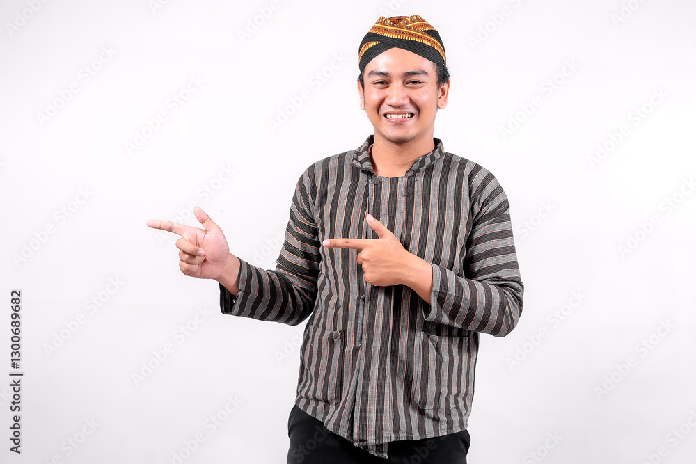 This photo features a young man wearing traditional lurik attire, smiling and gesturing with his hands, showcasing cultural pride and friendliness against a neutral background. This photo features a young man wearing traditional lurik attire, smiling and gesturing with his hands, showcasing cultural pride and friendliness against a neutral background.