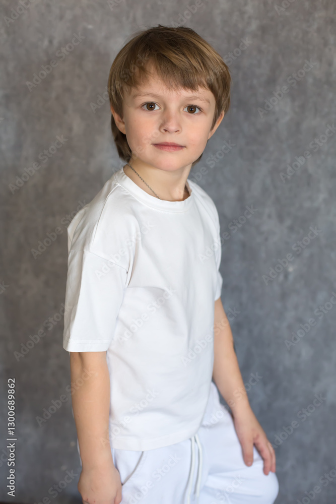 A handsome blond boy with big brown eyes wearing a white T-shirt and pants A handsome blond boy with big brown eyes wearing a white T-shirt and pants
