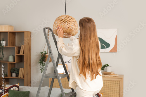Young woman screwing light ...