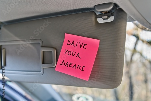 Sticky note with 'Drive Your Dreams' on car sun visor