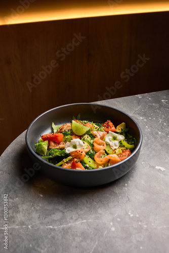 Obraz na płótnie Salmon, avocado, and tomato salad with lime in black bowl on marble table, healthy eating concept w salonie