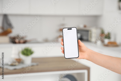 Woman with blank mobile phone in kitchen, closeup
