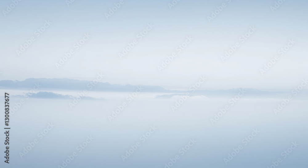 Fototapeta premium A serene and minimalist view of a mountain range barely visible through a thick layer of pale, wispy clouds
