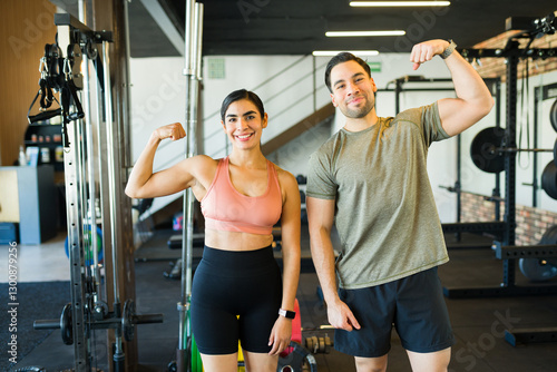 Wallpaper Mural Smiling hispanic man and woman flexing biceps and showing strength gains while working out together at gym Torontodigital.ca