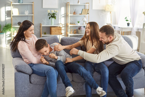 Billede på lærred Joyful funny family at home, parents and children adult happy excited tickling b