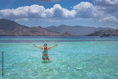 Obraz na płótnie A truly joyful, unforgettable moment at the beautiful beach, showcasing clear turquoise waters alongside a stunning mountain backdrop beneath a bright blue sky, Komodo, Indonesia w salonie