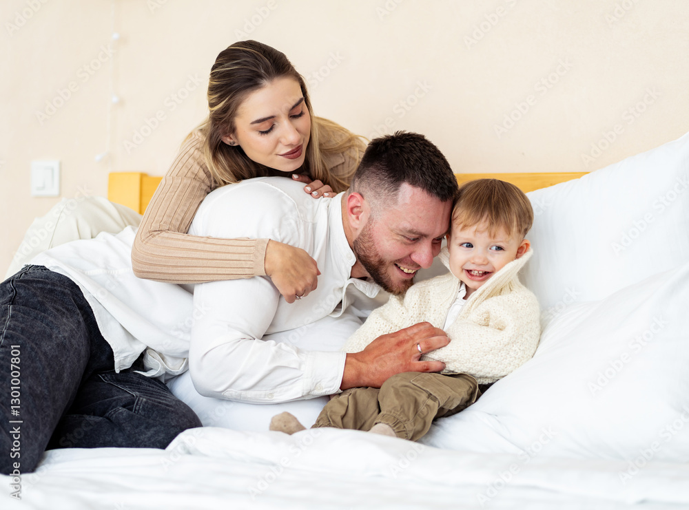Family enjoys playful moment on bed. Parents share a joyful moment with their child, engaging in playful affection on a cozy bed at home. Family enjoys playful moment on bed. Parents share a joyful moment with their child, engaging in playful affection on a cozy bed at home.