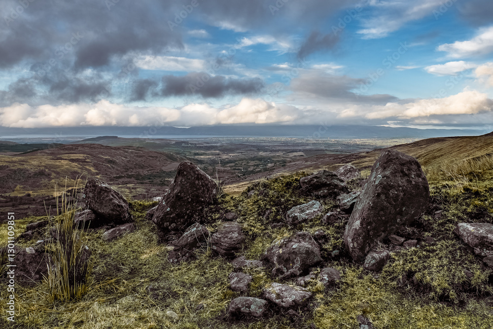 Elevated view. Numerous gray rocks scattered on a grassy hill. Distant valley and horizon visible. Elevated view. Numerous gray rocks scattered on a grassy hill. Distant valley and horizon visible.