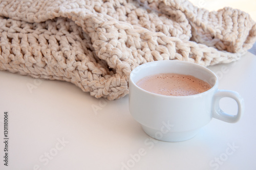 Cozy scene with cup of coffee and a knitted bag. Hygge style. Mug of black coffee standing on white table. Side view, vintage style. Still life photo