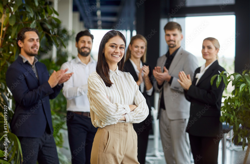 Portrait of a happy smiling confident business woman leader proudly looking at camera with a team of company employees applauding in background in office. Success and leadership concept. Portrait of a happy smiling confident business woman leader proudly looking at camera with a team of company employees applauding in background in office. Success and leadership concept.