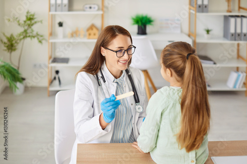 Fotografia Friendly smiling woman doctor pediatrician with tongue depressor asks child to o