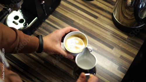 Bartender adds milk to the coffee from the milk jug and draws a heart on it. High quality 4k footage