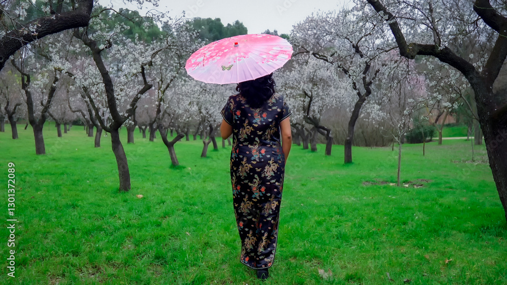 Woman with pink parasol walking in quinta de los molinos park in madrid
