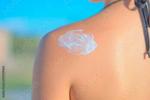 Aesthetic portrait of a beautiful girl, placing sunscreen on her shoulder, girl's hand applying, putting moisturizer on her arm