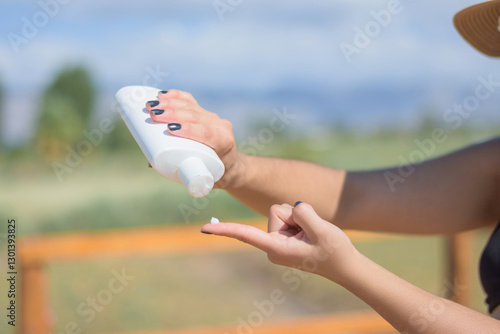 The woman applies sunscreen and takes care of her skin to protect her skin from UV rays. She put sunscreen on her arms and hands.