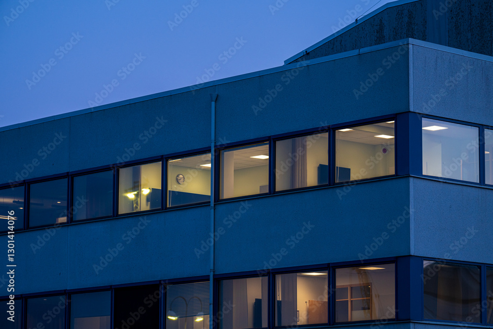 Fototapeta premium office building at dusk with lit windows.