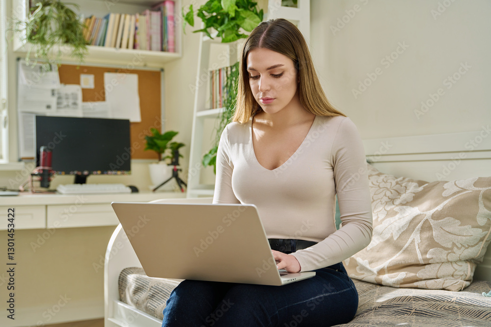 Young woman working at home, sitting on couch using laptop Young woman working at home, sitting on couch using laptop