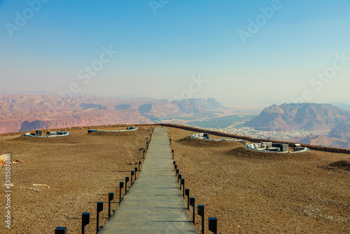 Pathway leading to a viewpoint overlooking AlUla Old Town, surrounded by Saudi Arabia's breathtaking desert landscapes and mountains, offering a panoramic vista under a clear blue sky of Saudi Arabia