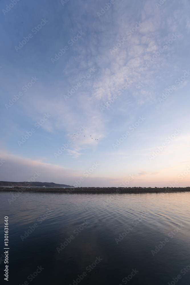 Fototapeta premium 北海道の網走の道の駅の裏の港のフェリーや漁船と朝焼けの空と朝日