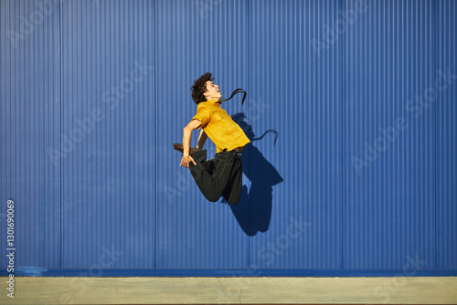 Quadro em tela Student performing an energetic jump against a vibrant blue backdrop showcasing