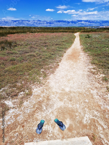 Wooden boardwalk through marshland with abandoned flip-flops in foreground