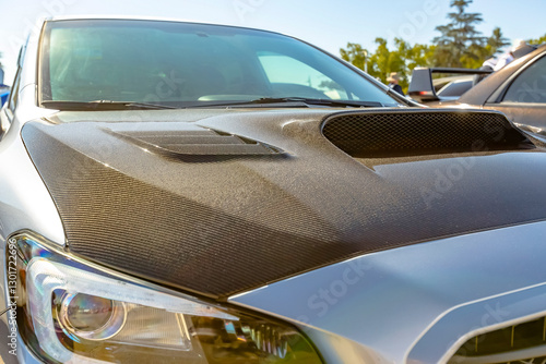 Carbon fiber hood on a white car photo