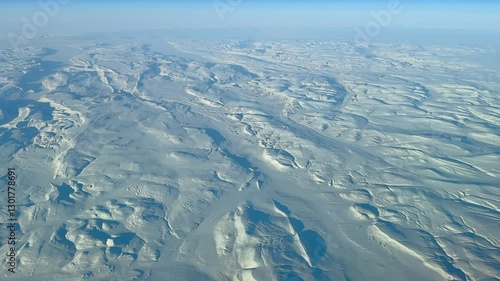 high level flying across Canadian tundra landscape in Nunavut and Northwest Territories with fully snow-covered mountains and deeply frozen lakes and rivers - wide angel 4k aerial video footage