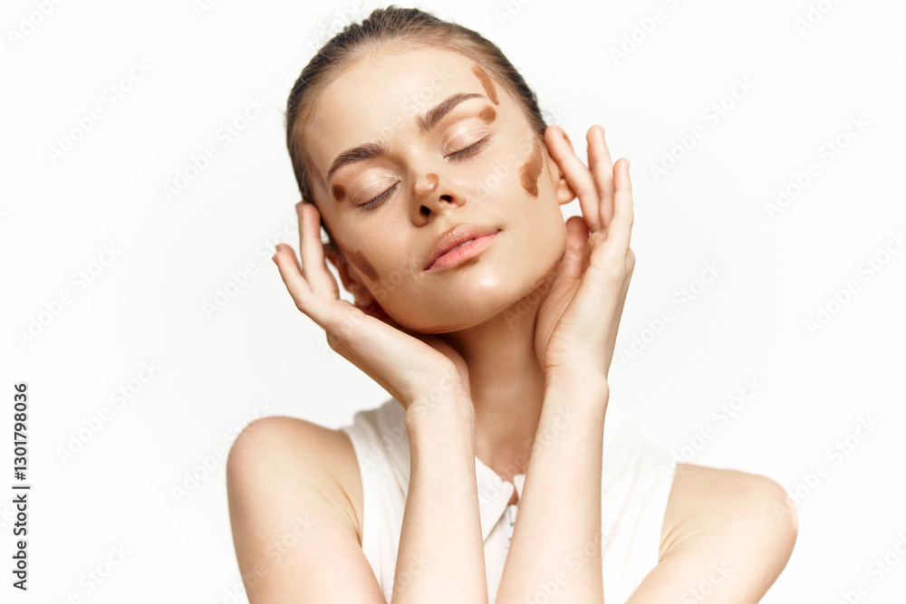 Beautiful model applying foundation on her face, showcasing a natural makeup look with soft lighting and subtle colors. Beautiful model applying foundation on her face, showcasing a natural makeup look with soft lighting and subtle colors.