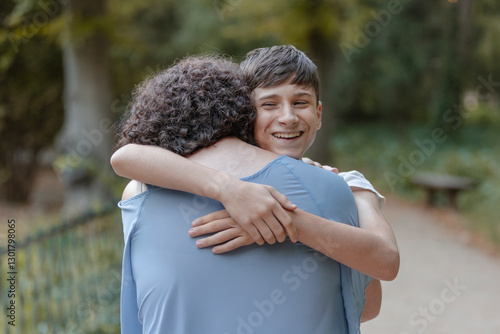 Hug from a happy teenage son to his mother. Tenderness, love, family.