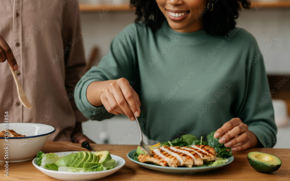 African female adult preparing grilled chicken salad with avocado in kitchen African female adult preparing grilled chicken salad with avocado in kitchen