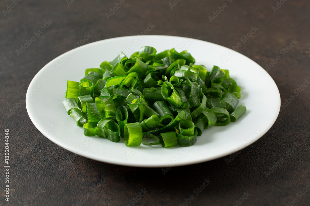 A view of a pile of chopped scallions, on a plate. A view of a pile of chopped scallions, on a plate.