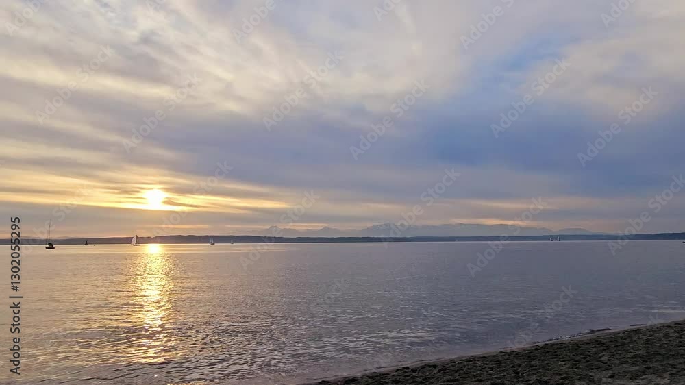 Panning shot of the beach with an orange sunset and the Olympic Mountains in the background Panning shot of the beach with an orange sunset and the Olympic Mountains in the background