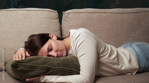 Weary professional reclining on plush sofa, gradually surrendering to drowsiness, experiencing momentary tranquility amid hectic daily routine, finding quiet respite and deep relaxation